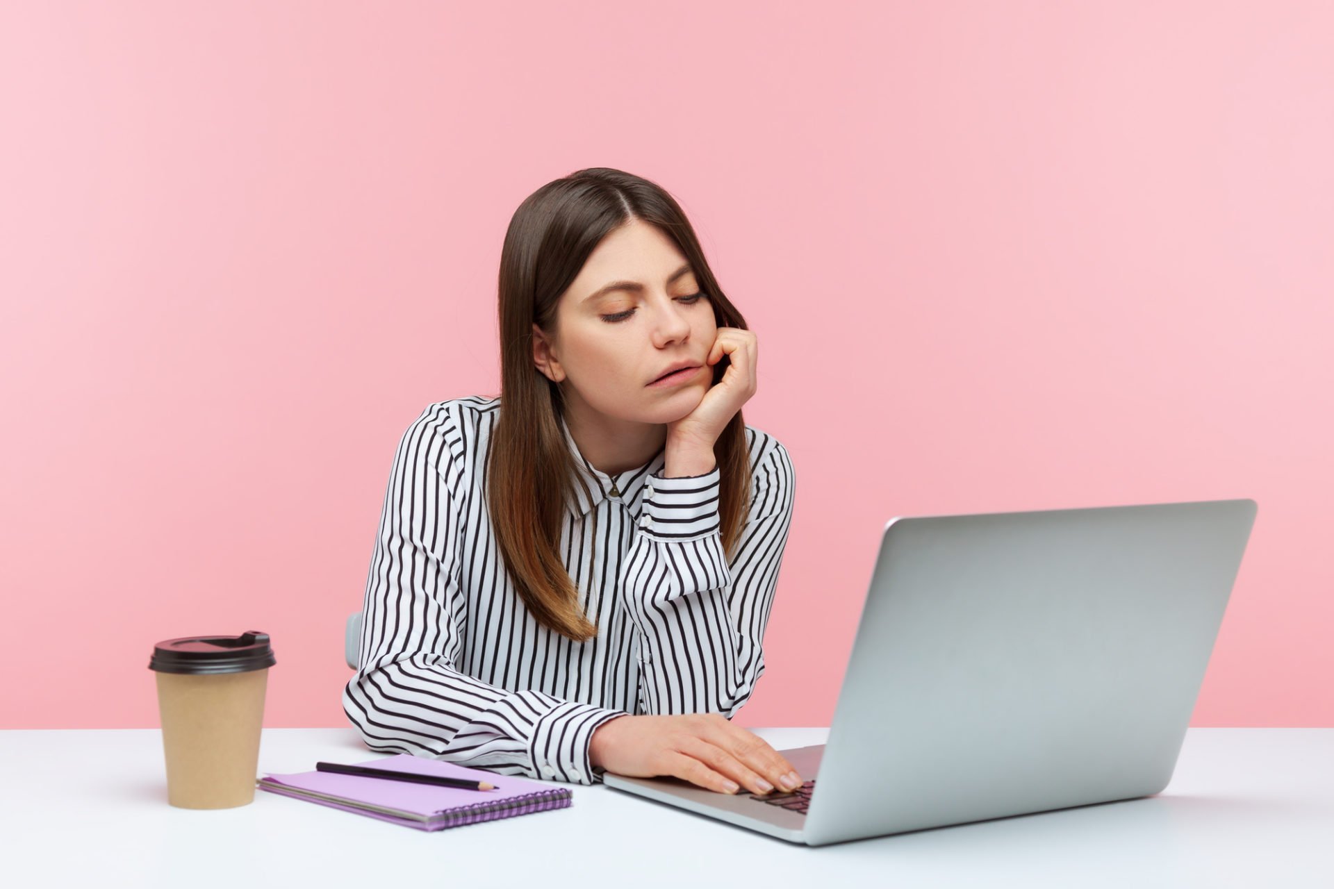 Bored unhappy business woman sitting at workplace looking at lap